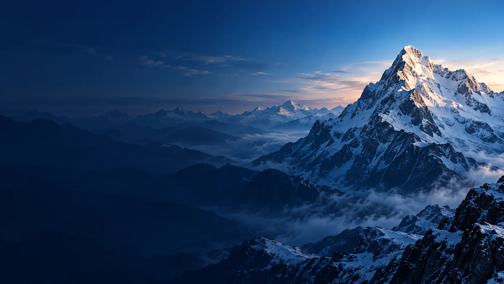 Snow-covered alpine summit above layers of blue mountain ridges.